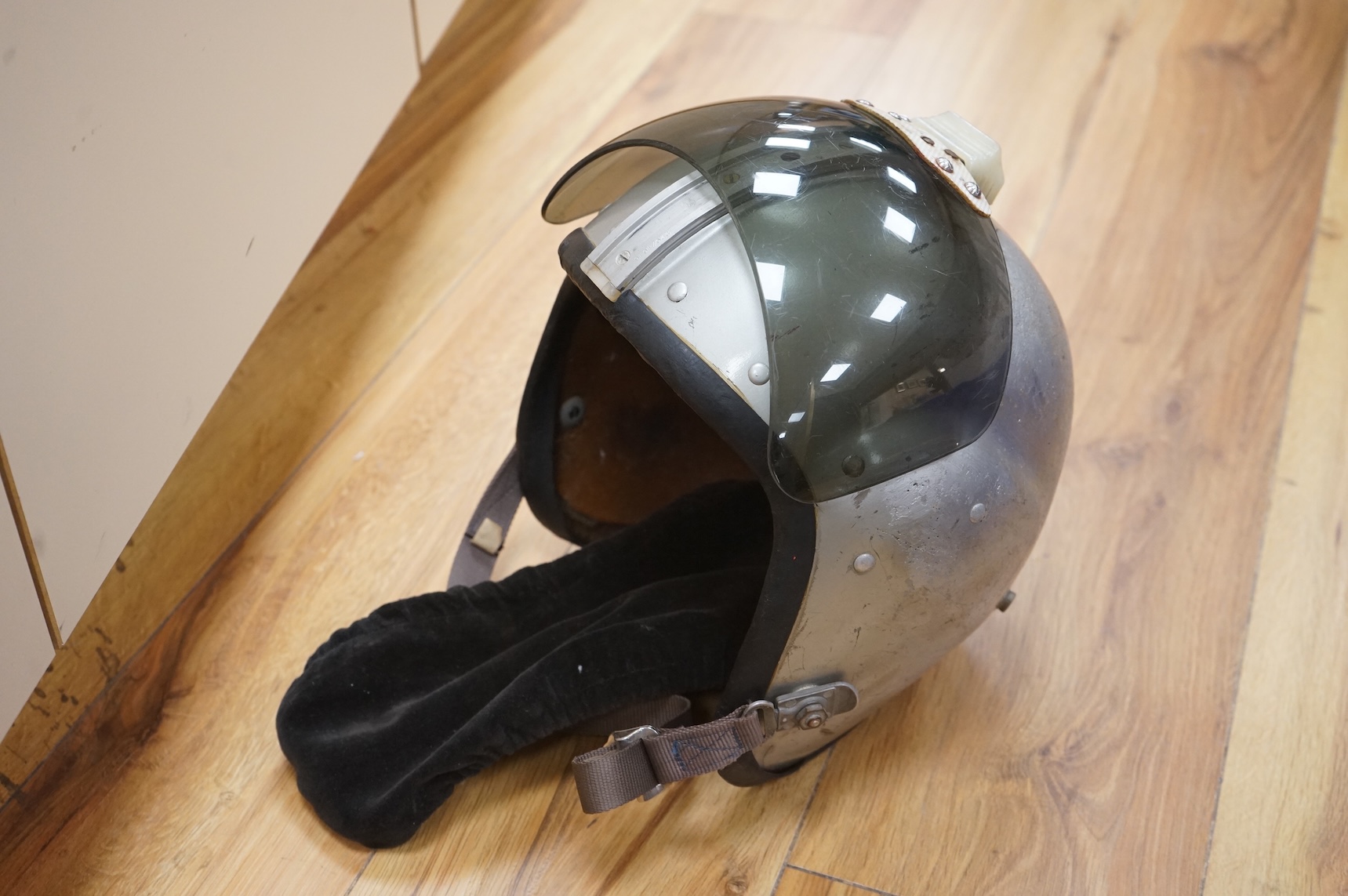 An early British jet aircraft RAF flying helmet, size 3 regular, dated 1958, with visor and visor cover, and original interior webbing, complete with inner cloth flight cap with built-in headphones and electrics and date